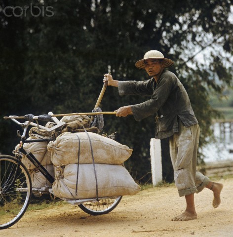 Một người dân Việt Nam vận chuyển gạo bằng loại xe cải tiến (xe thồ) trên đường Quốc lộ 1, con đường dài 1.500km được người Pháp xây dựng và trở thành con đường chiến lược trong chiến tranh Việt Nam.